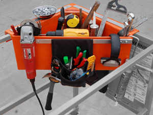 A red aerial tool bin attached to the corner of a lift. Inside it are several tools and a tool pouch is hanging off the front.