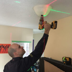 Electrician using driller's dust bowl with a hole saw to drill a pot light hole.