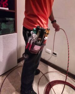 An electrician using a fish tape to pull wire through a wall.