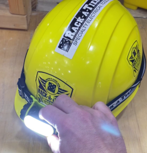rack-a-tiers rechargeable head light on a hard hat. the hard hat is yellow and has 3 rack-a-tiers stickers.