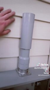 a pvc expansion coupling installed on an electrical service outside of a house.